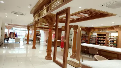 Carved wooden pillars and arches with a tall mirror between them, inside the showroom.